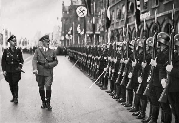 Hitler caminhando em frente a tropas nazistas, em texto sobre História Geral.